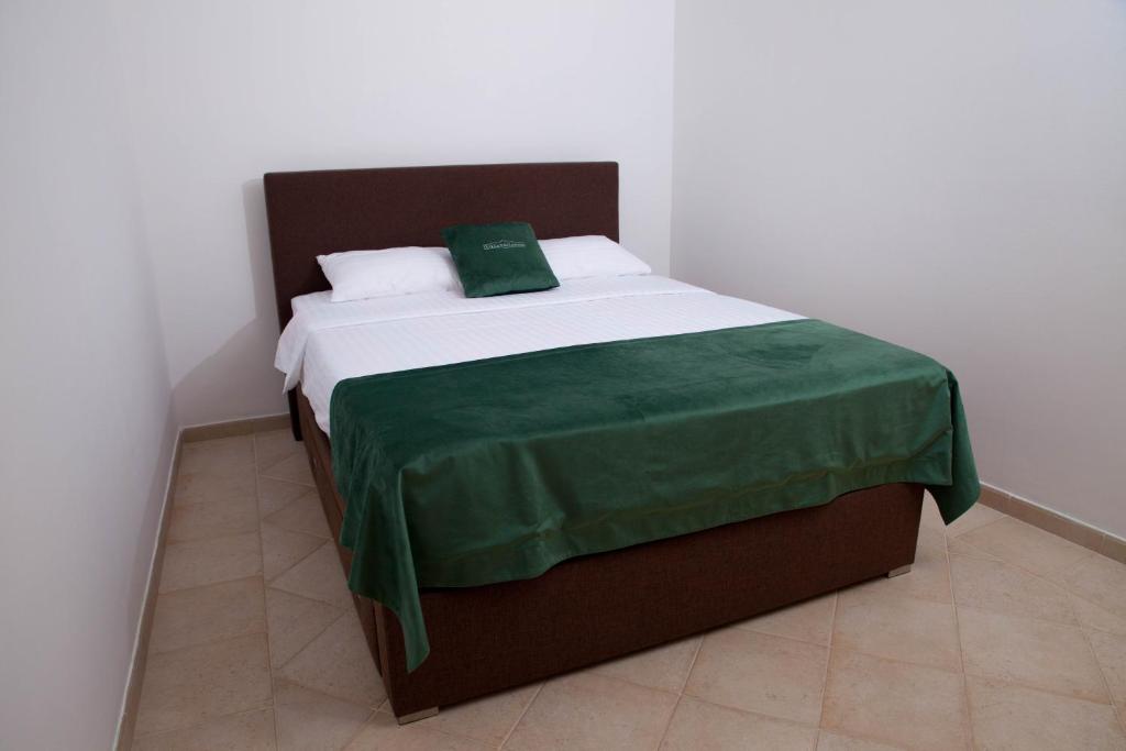 a bedroom with a bed with a green blanket on it at Villa Edelweiss in Sveti Stefan