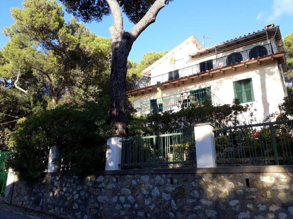 a white house with a tree in front of a fence at Casa al mare Livorno in Quercianella