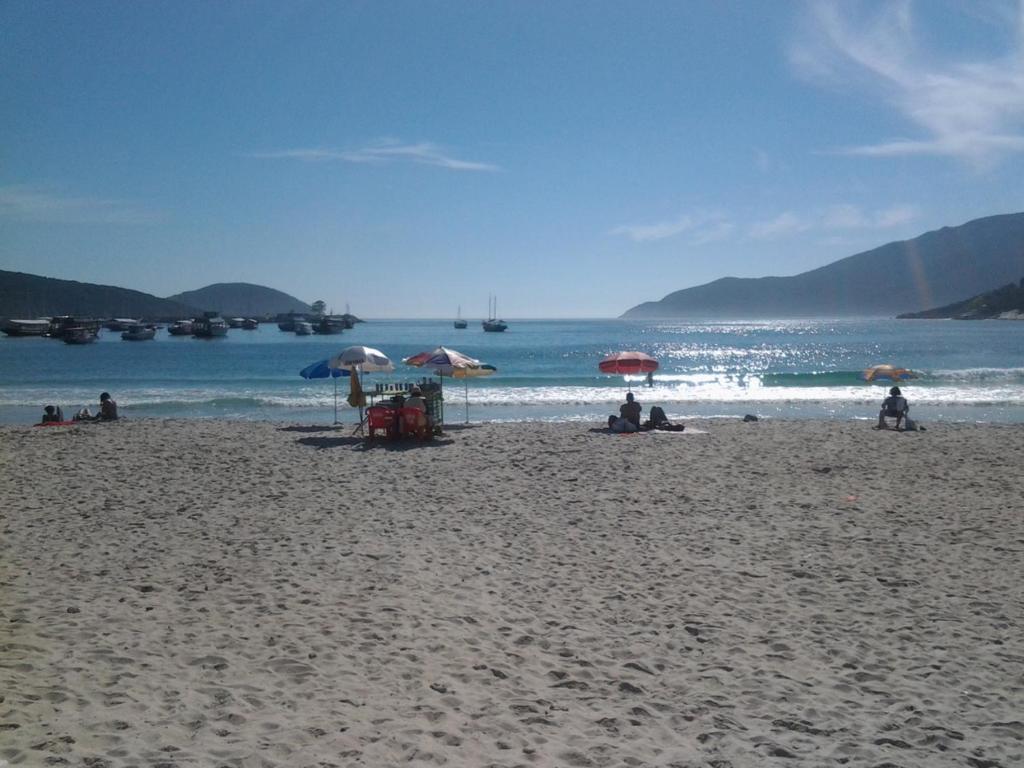 eine Gruppe von Menschen, die am Strand mit Sonnenschirmen sitzen in der Unterkunft Caribe Brasileiro in Arraial do Cabo