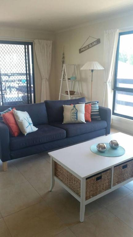 a living room with a blue couch and a coffee table at Pebbles Beach Retreat in Cowes