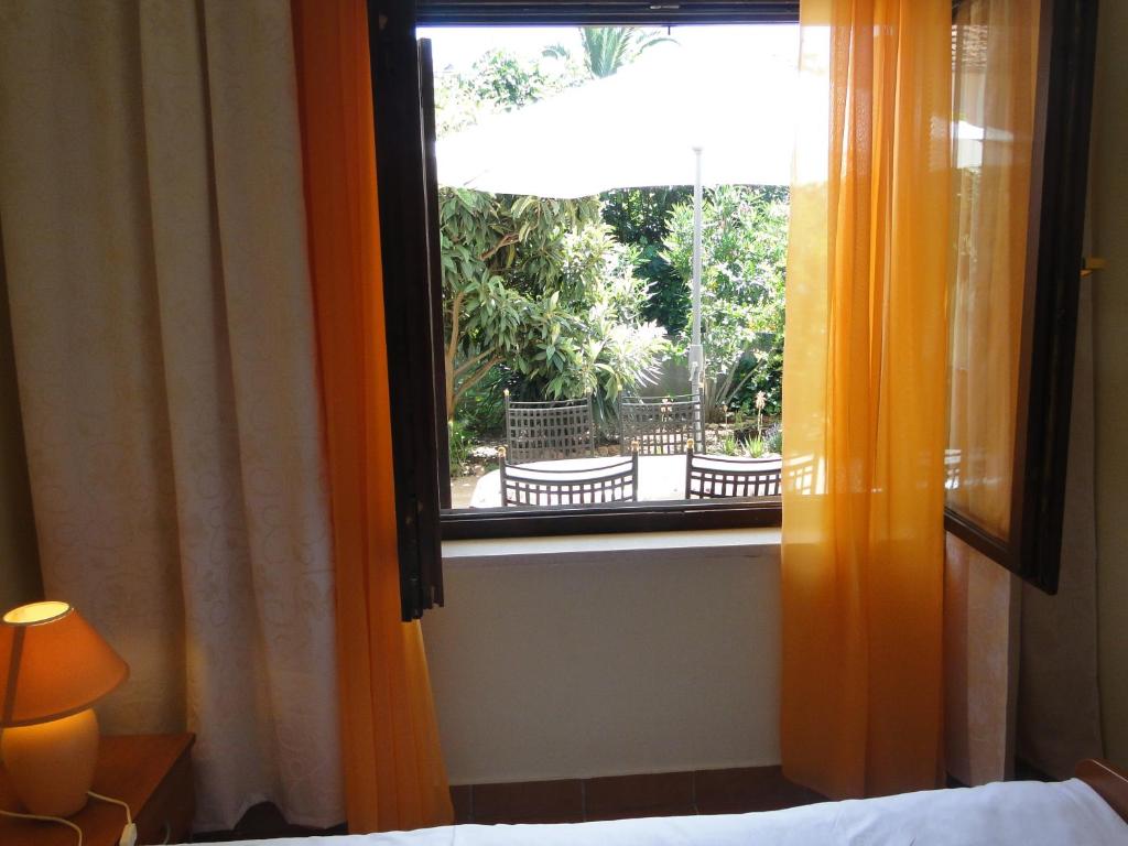 a bedroom window with an orange curtain and a bed at Villa Agava in Vrboska