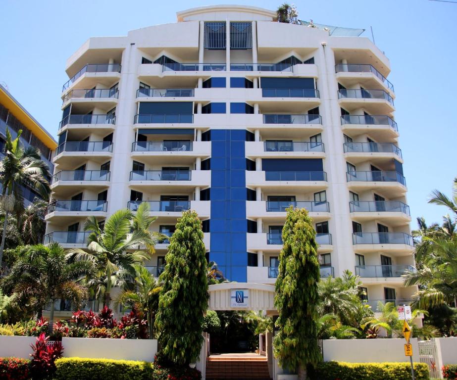 a tall white building with trees in front of it at 181 The Esplanade in Cairns