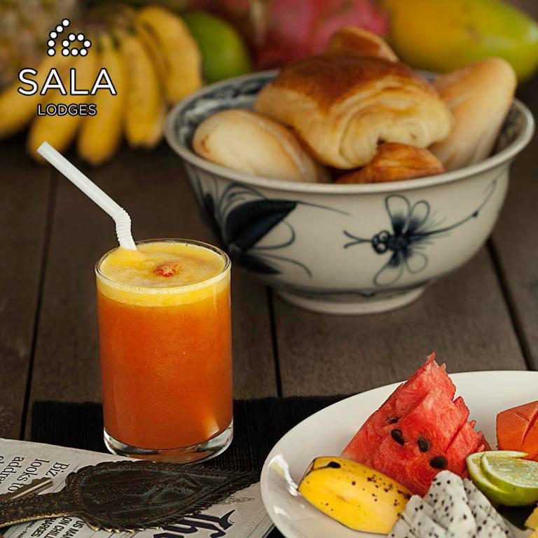 a bowl of fruit and a glass of juice and a bowl of food at Sala Lodges in Siem Reap