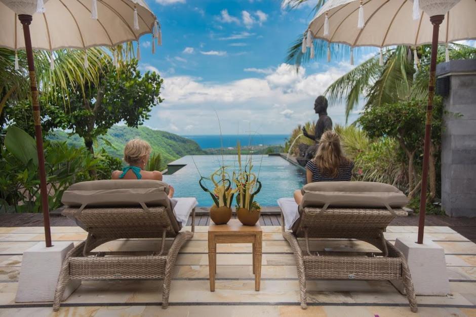 people sitting on a patio with a view of the ocean at Bella Kita Mountain Retreat & Spa in Klungkung