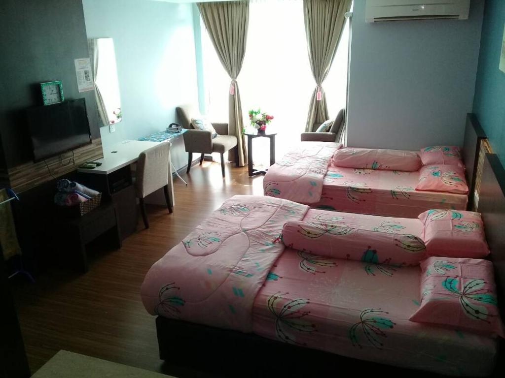 a bedroom with two beds and a desk and a television at Best Studio Guest House in Kota Bharu