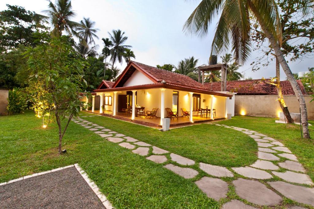 a villa with a garden and a house at Fantasea in Mirissa