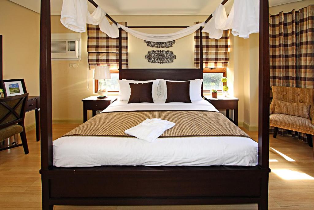 sypialnia z łóżkiem z baldachimem i biurkiem w obiekcie Crosswinds Resort Suites w mieście Tagaytay