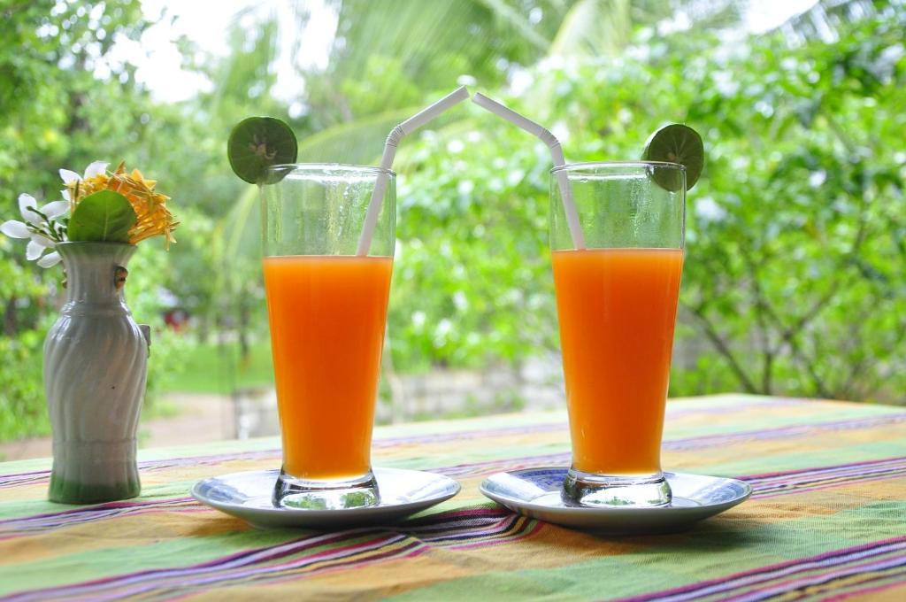 two glasses of orange juice sitting on a table at Rock Lake Home Stay in Sigiriya