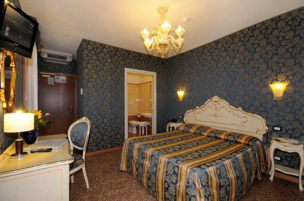 ヴェネツィアにあるホテル イル メルカンテ ディ ベネツィアのベッドとテレビが備わるホテルルームです。
