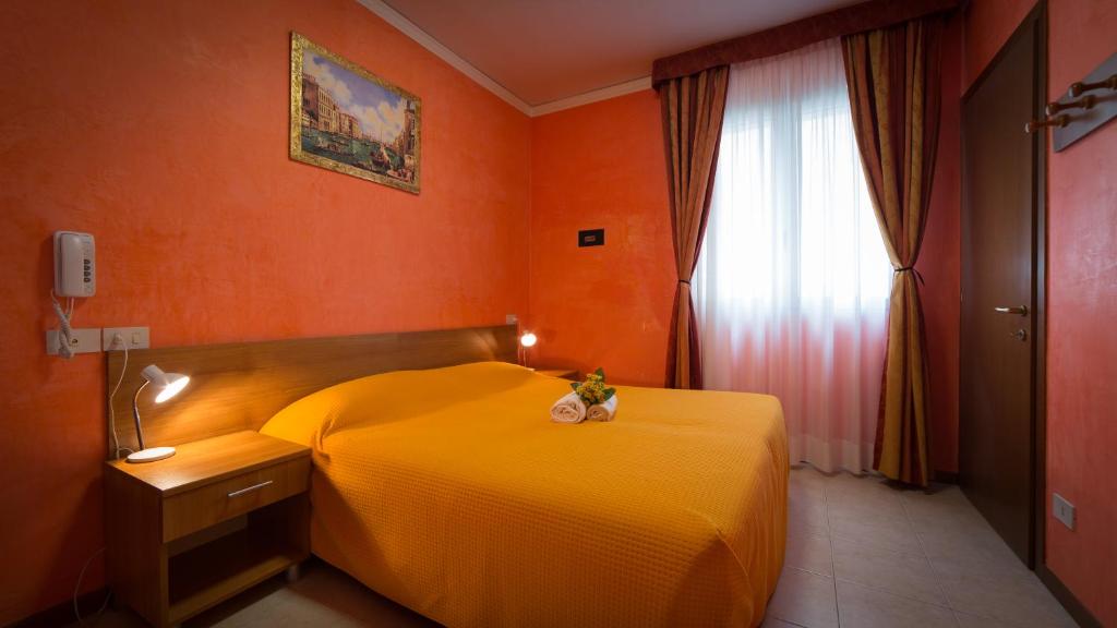 a bedroom with a yellow bed and a window at Hotel Venezia in Caorle