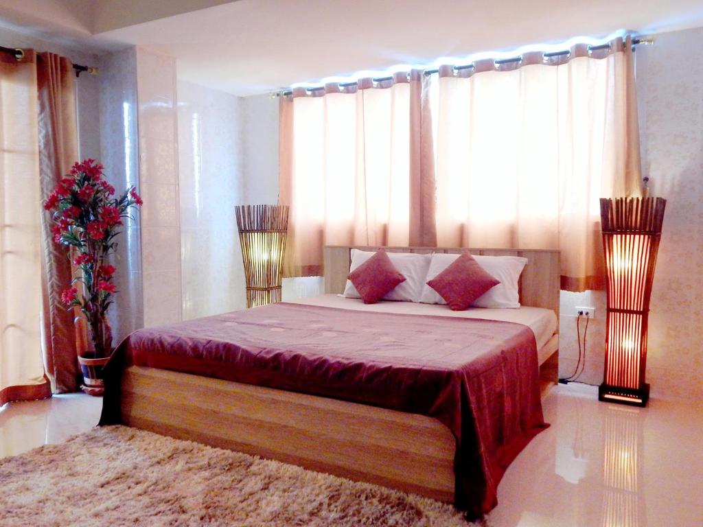 a bedroom with a large bed with red sheets and pillows at D5 Hotel สาขา หนองตำลึง in Chon Buri