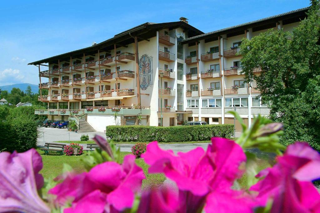 un grande edificio con fiori rosa di fronte di Hotel Kanz a Egg am Faaker See