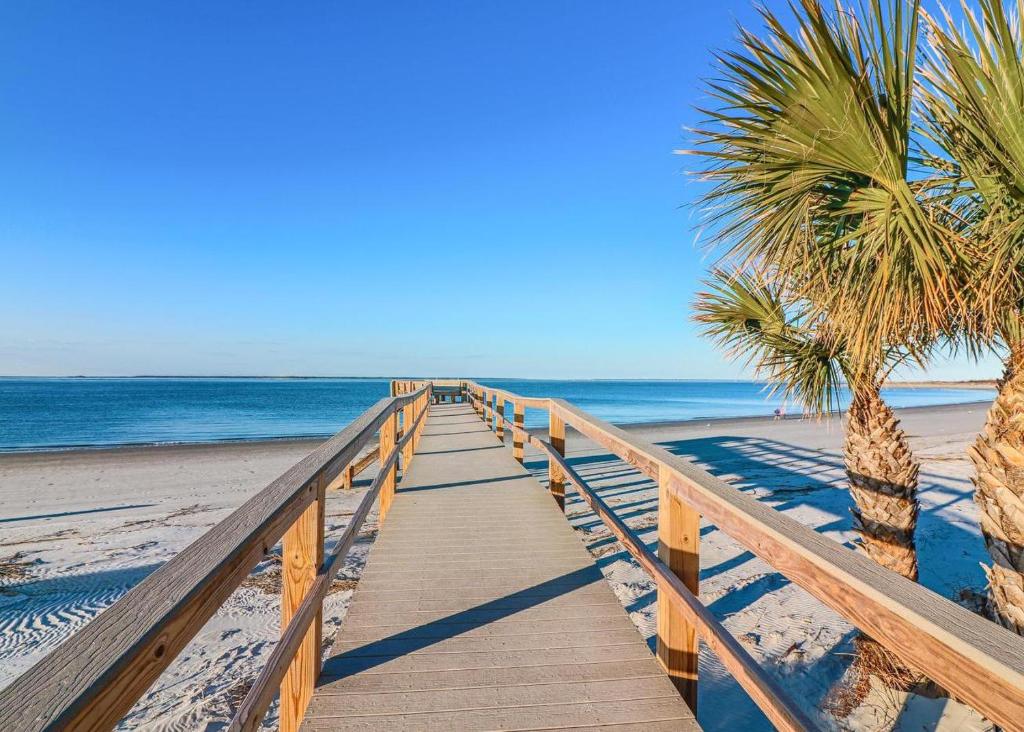 a wooden pathway to the beach with palm trees at Forever Summer in Tybee Island