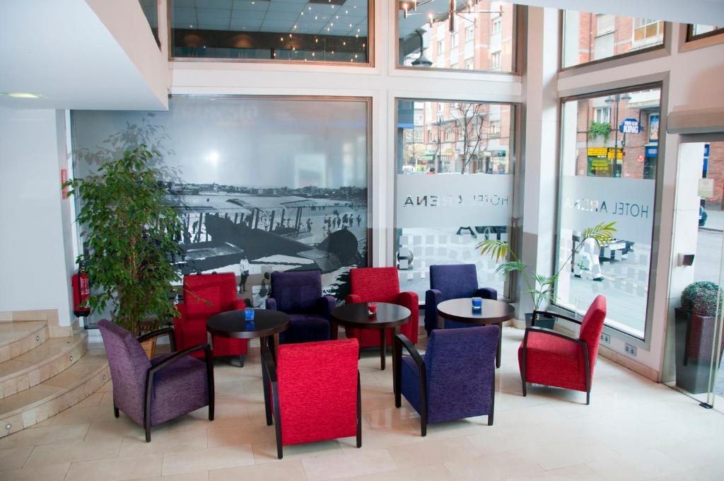 un restaurante con mesas y sillas rojas y azules en Hotel Arena, en Gijón