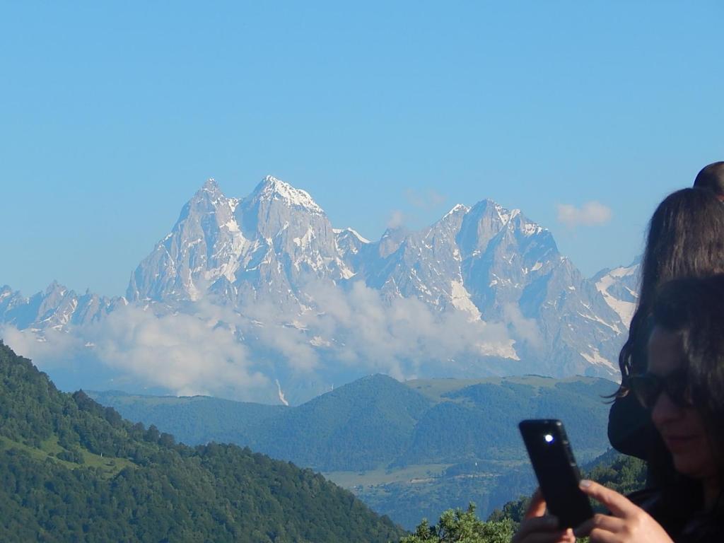 two women looking at a cell phone in front of a mountain at Marina's guest house in Lentekhi