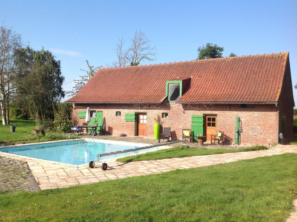 a house with a swimming pool in front of it at le gite "des voyageurs" in Wormhout