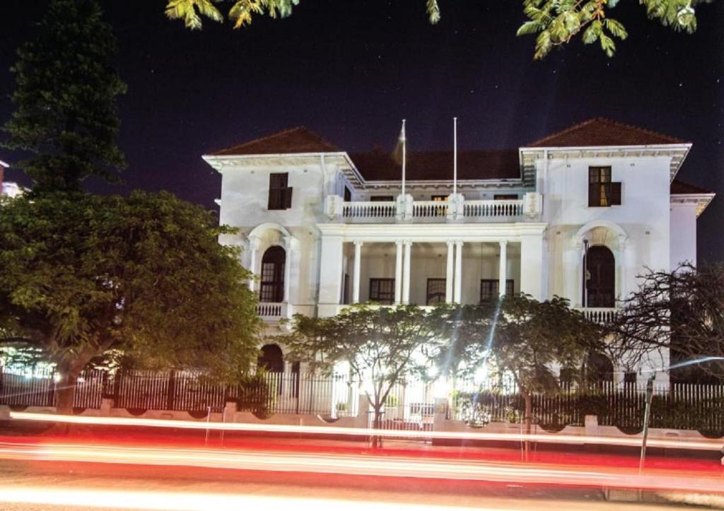 ein weißes Gebäude in der Nacht mit einer Straße vor dem Haus in der Unterkunft Bulawayo Club in Bulawayo