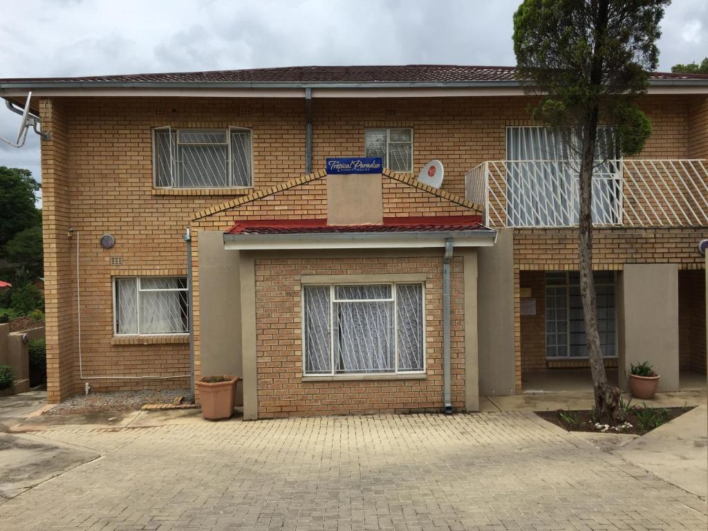 a brick house with a blue street sign on it at Tropical Paradise Guest House in Nelspruit