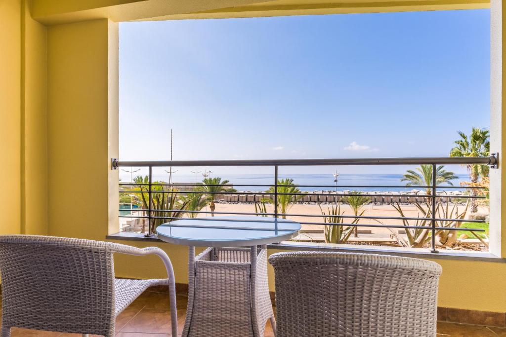 a balcony with a table and chairs and a view of the beach at Calheta Beach - All-inclusive - Savoy Signature in Calheta