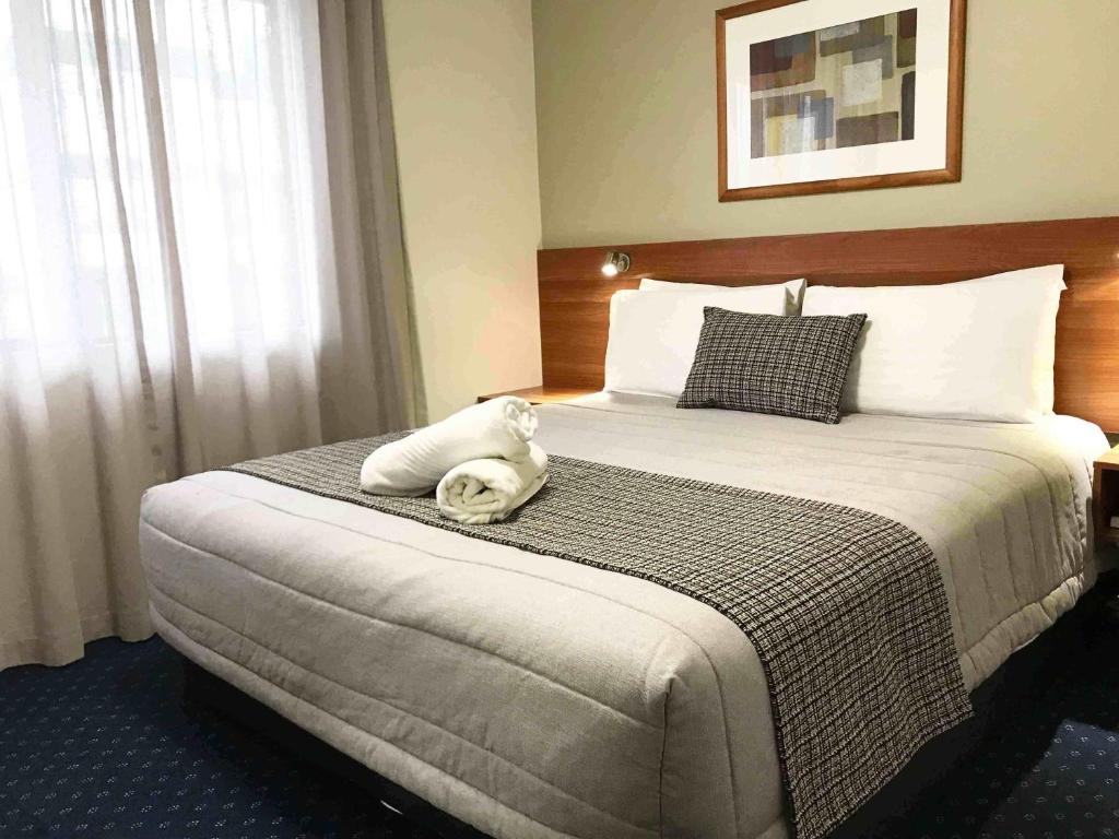a hotel room with a bed with a stuffed animal on it at Ventura Inn & Suites Hamilton in Hamilton