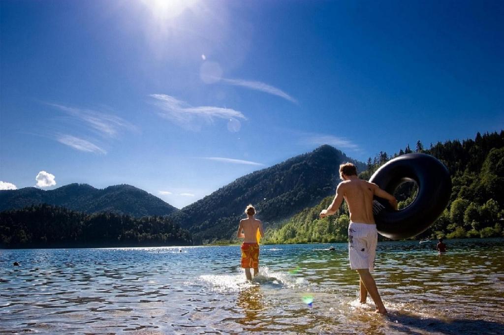 two men standing in the water with a tire at DEVA Hotel Kaiserblick in Reit im Winkl