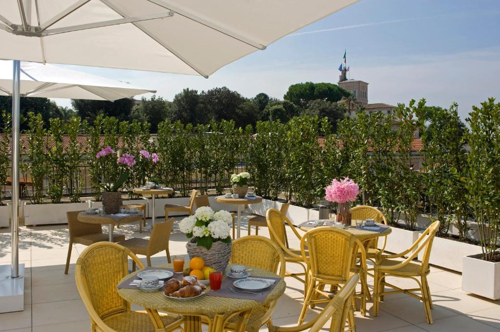 un patio con mesas, sillas y una sombrilla en Hotel De Petris en Roma