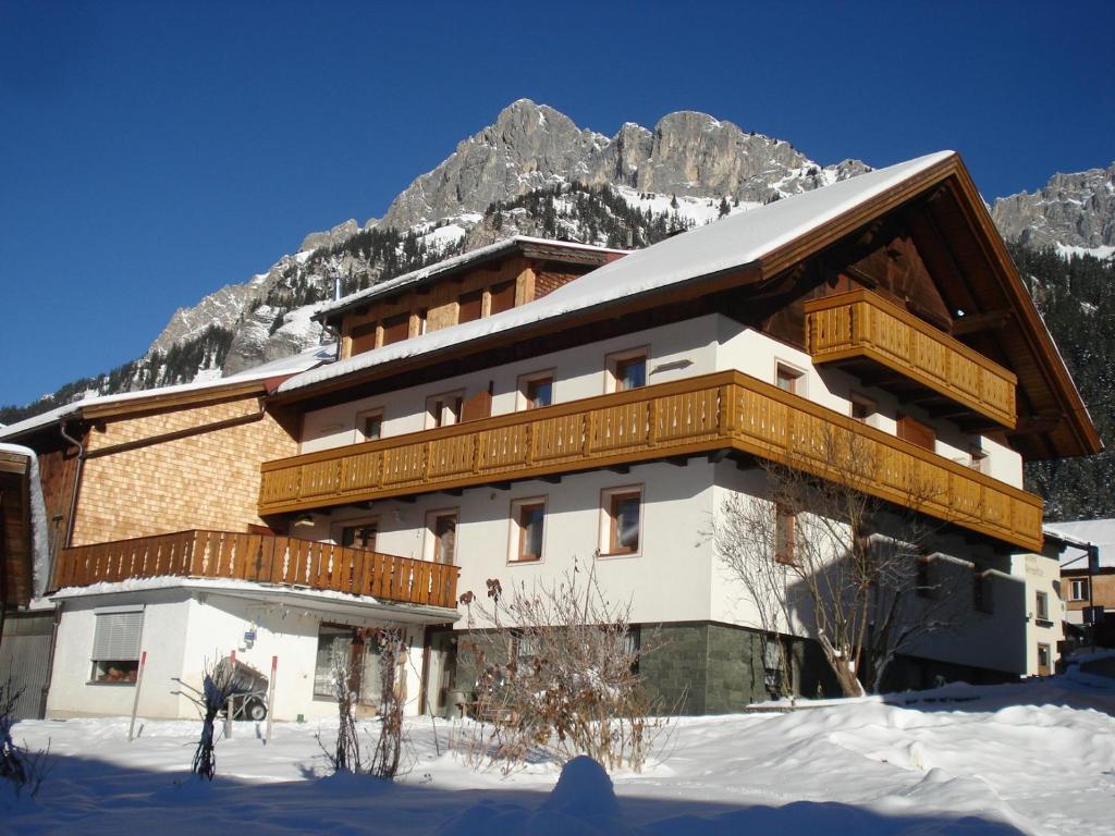 a building in the snow with mountains in the background at Haus Walter in Nesselwängle