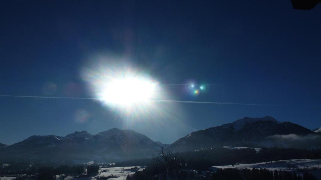 a sun is shining in the sky over mountains at Apartement Hasenauer in Fieberbrunn