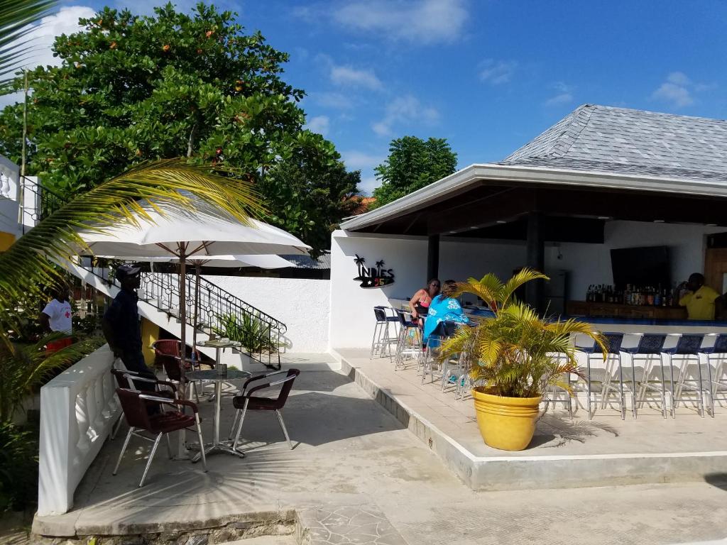 un patio con mesas y sillas y un bar en White Sands Negril, en Negril