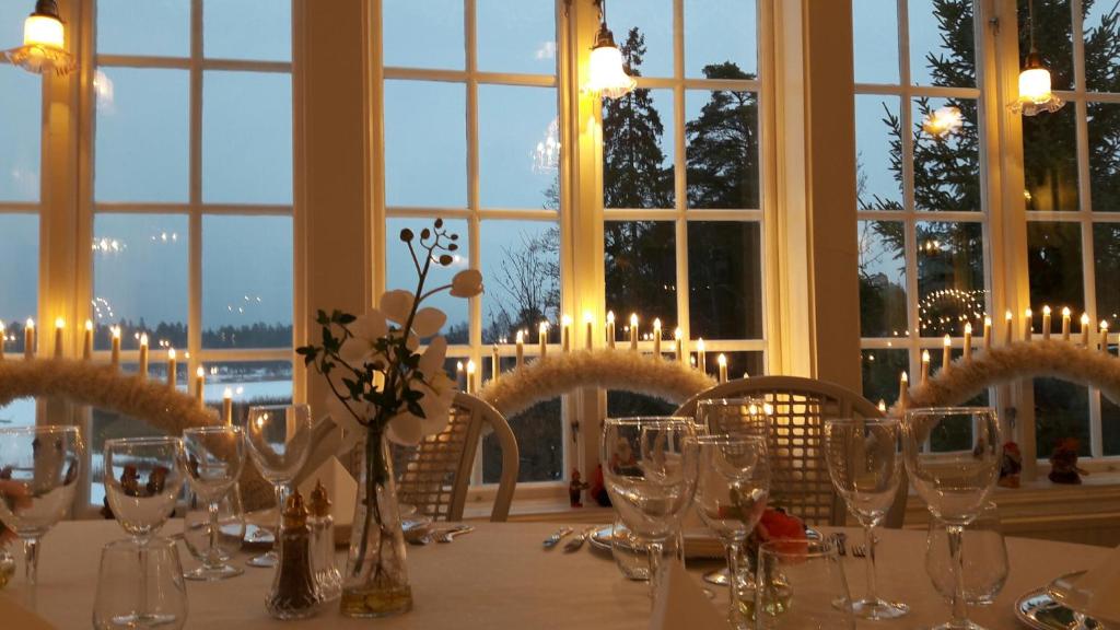 - une table avec des verres et des fleurs dans une chambre avec des fenêtres dans l'établissement Odalgården Hotell, Kurs & Konferens, à Marielund