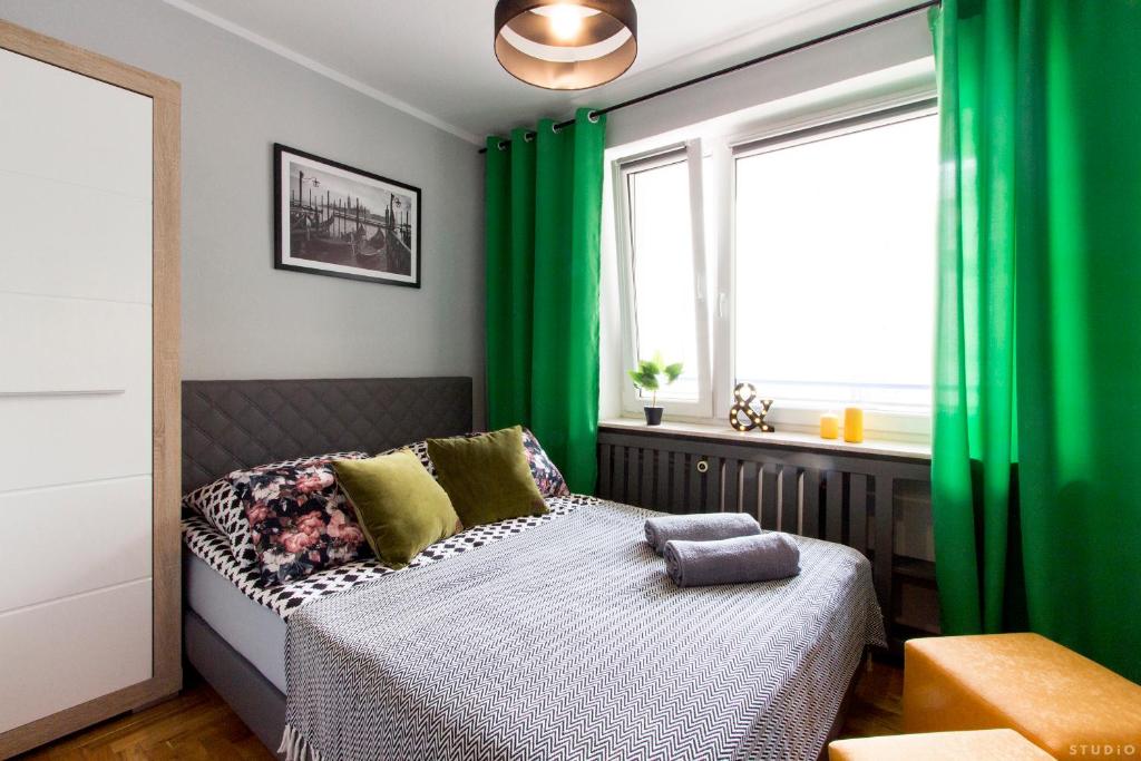 Schlafzimmer mit grünen Vorhängen und einem Bett mit Fenster in der Unterkunft ClickTheFlat Hoża Street Apart Rooms in Warschau