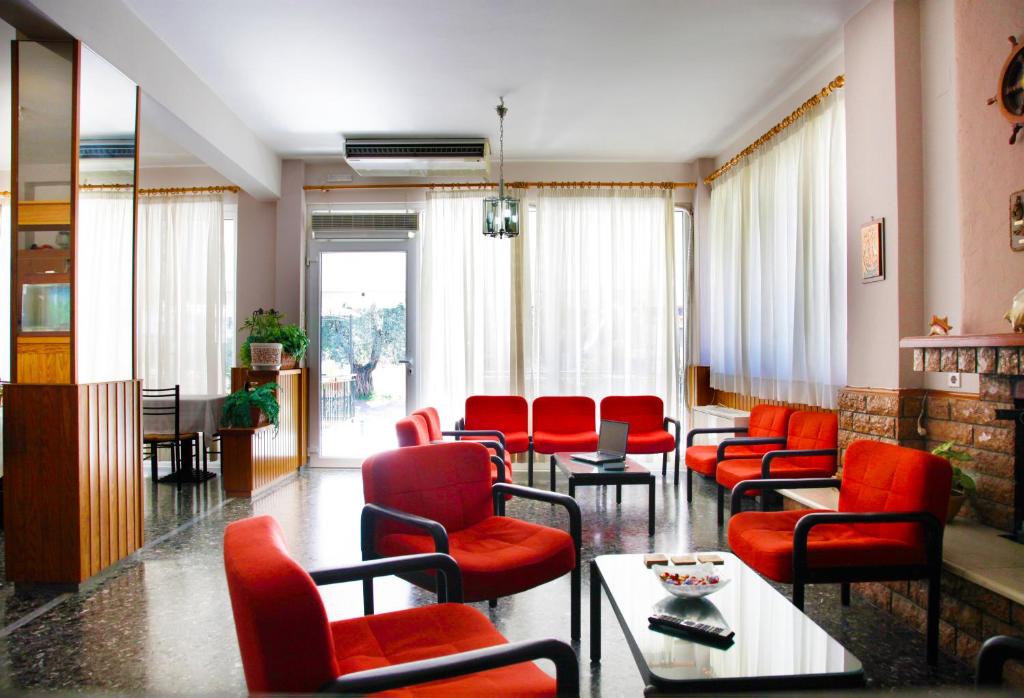 a waiting room with red chairs and tables at Noufara Hotel in Kamena Vourla
