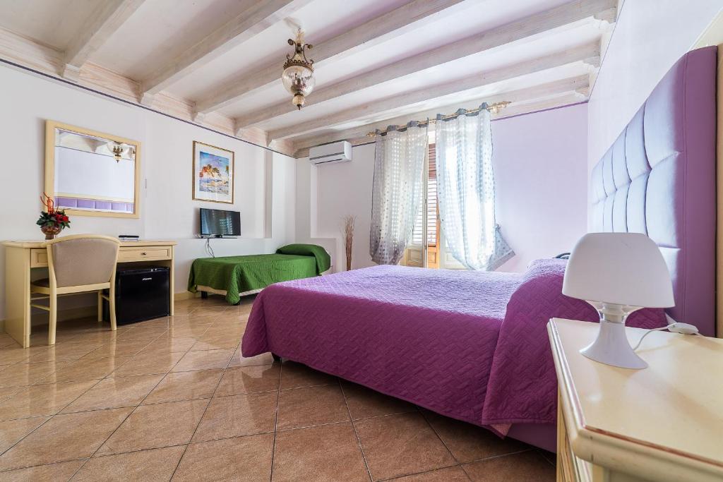 a bedroom with a purple bed and a desk at Hotel Centrale Bagheria in Bagheria