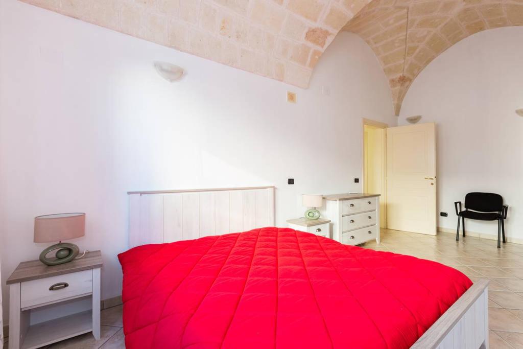 1 dormitorio con cama roja, escritorio y silla en Casa Sardelli en San Vito dei Normanni