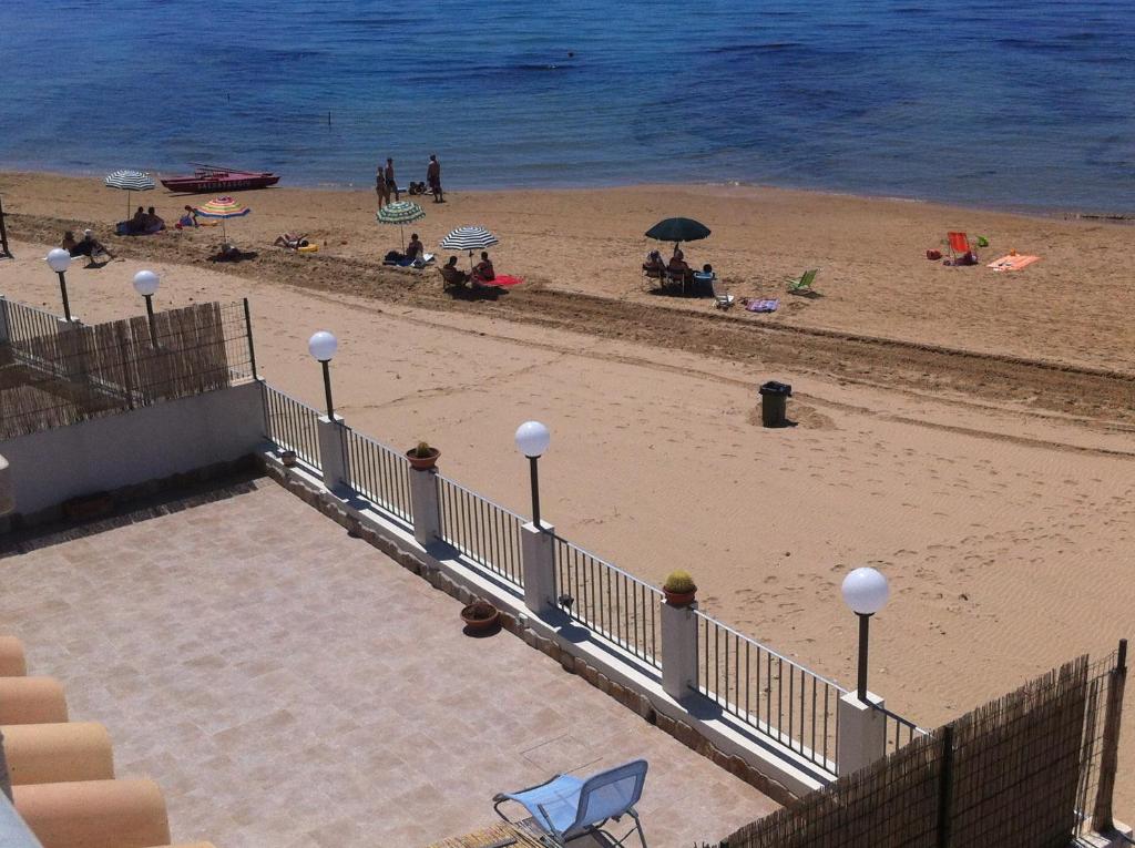 ポルト・エンペードクレにあるCasa Vacanze A Due Passi Dal Mareの砂浜と水辺に座る人々のいる浜