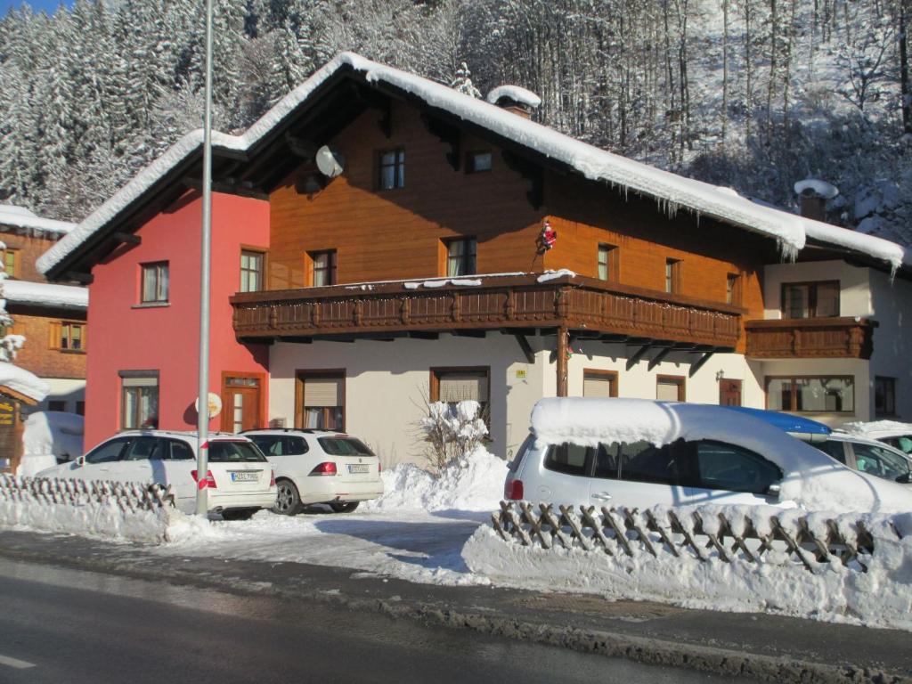 una casa cubierta de nieve con coches aparcados delante en Villa Familia, en Bartholomäberg