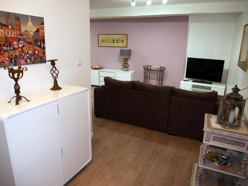 een woonkamer met een bank en een tv bij Maison Authier in Périgueux