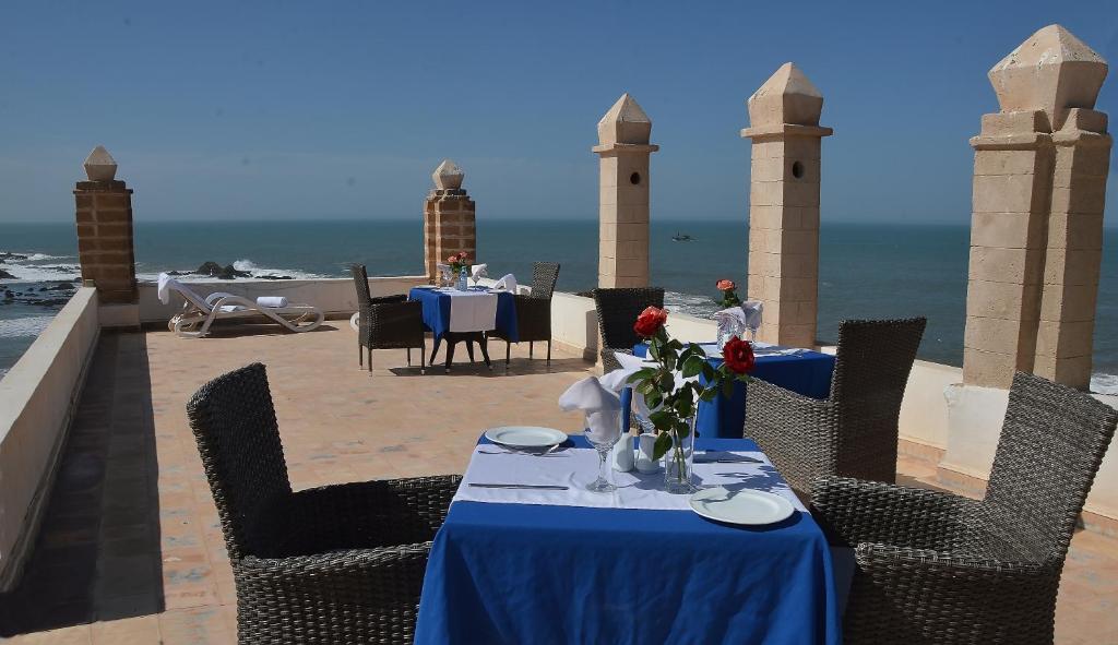 einen Tisch mit einem blauen Tischtuch und Stühlen sowie Meerblick in der Unterkunft Palais Des Remparts in Essaouira