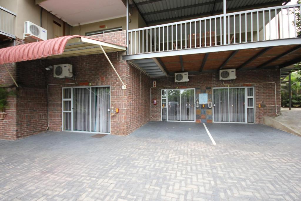 ネルスプロイトにあるIngwe Guesthouseのレンガ造りの建物で、2つのドアとバルコニーが付いています。