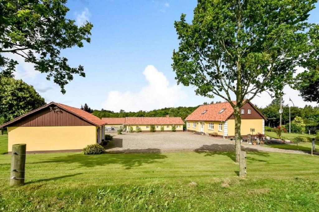 un gran patio con dos edificios y un árbol en Smidstrupvej 3 - The Lodge en Gadbjerg