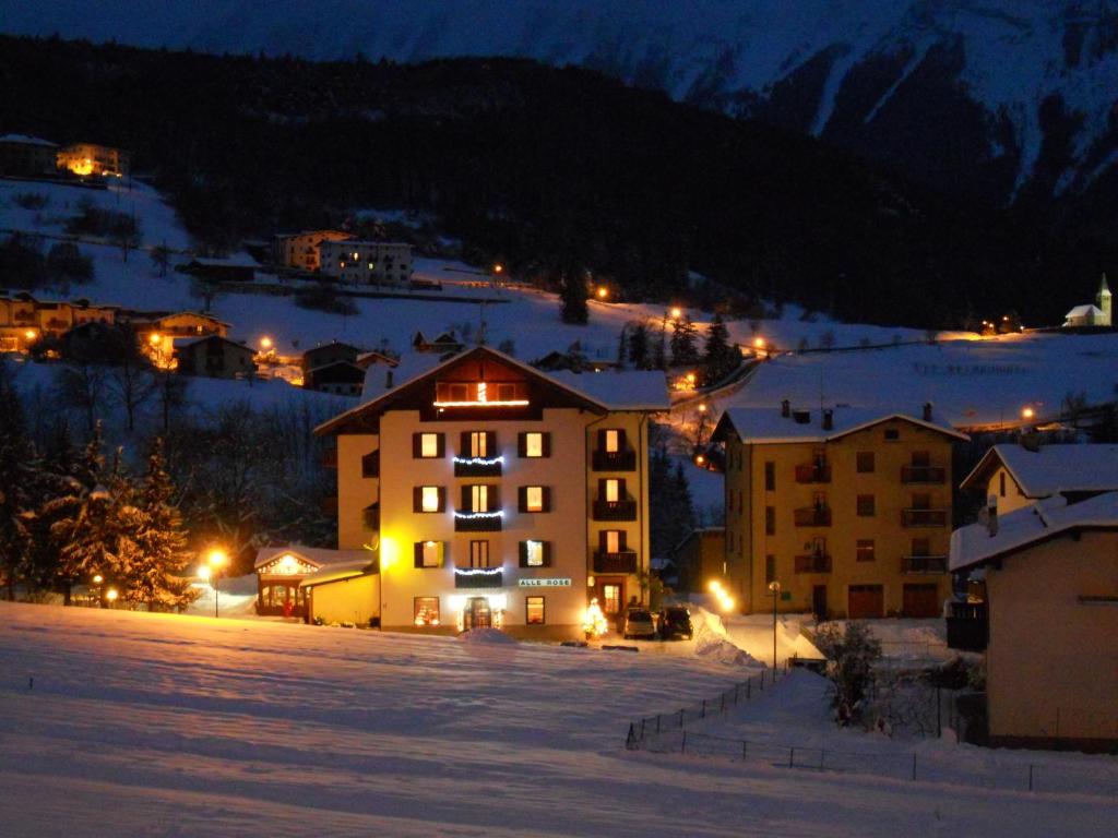 una ciudad en la nieve por la noche con edificios en Hotel alle Rose, en Cavedago