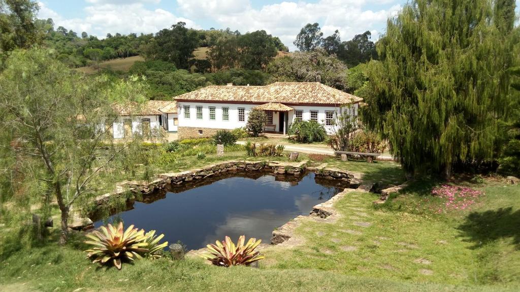 a house with a stone bridge over a pond at Hotel Fazenda Palestina in Itapecerica