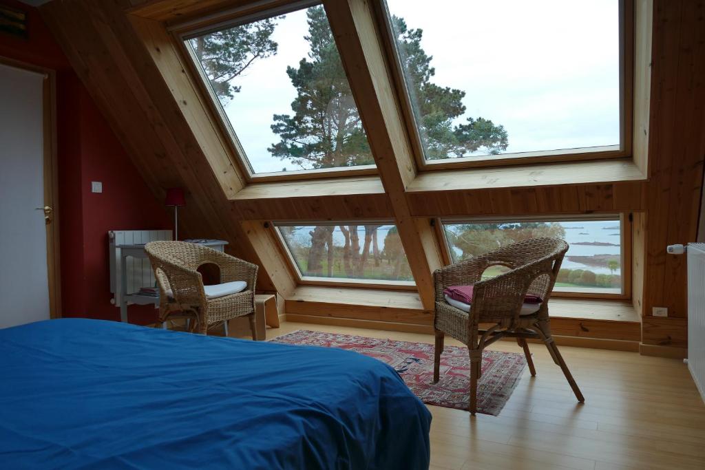 a bedroom with a bed and two chairs and windows at Cosmeur B&B in Carantec