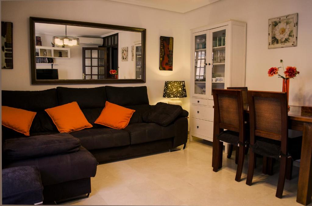 a living room with a black couch and a mirror at La Casa de los Arbolitos in Fuengirola
