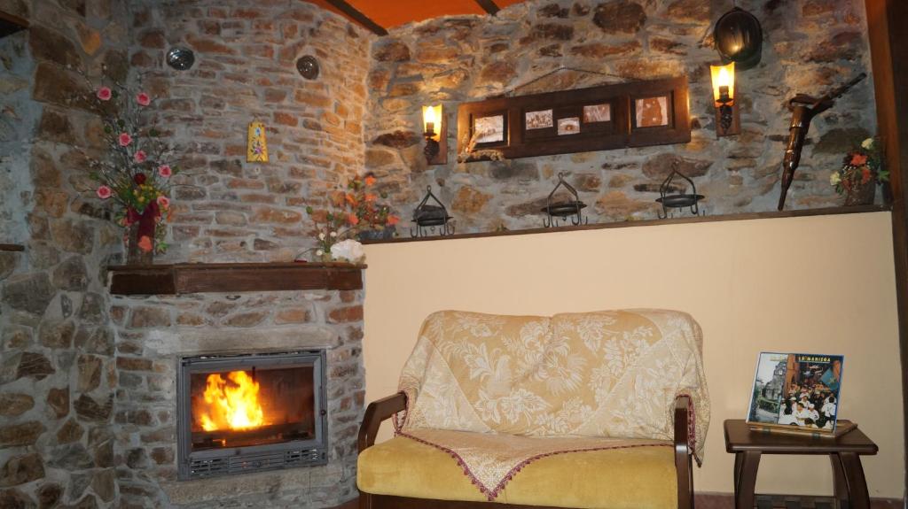 sala de estar con chimenea de piedra y silla en La Artesana en Posada de Rengos