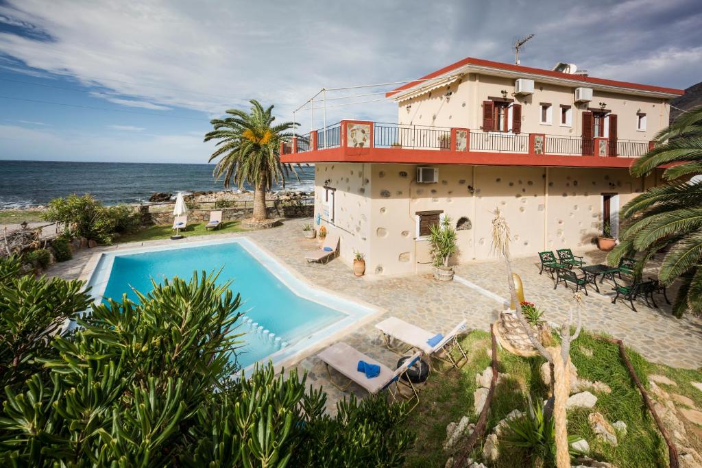 a house with a swimming pool next to the ocean at Pericles Beach Villa in Kissamos