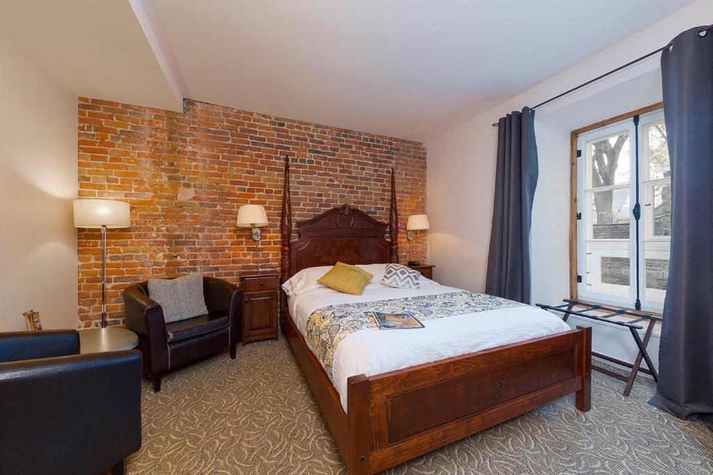 a bedroom with a bed and a brick wall at Le Coureur Des Bois in Quebec City