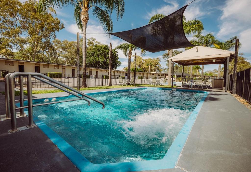a swimming pool at a resort with palm trees at Artesian Spa Motel in Moree