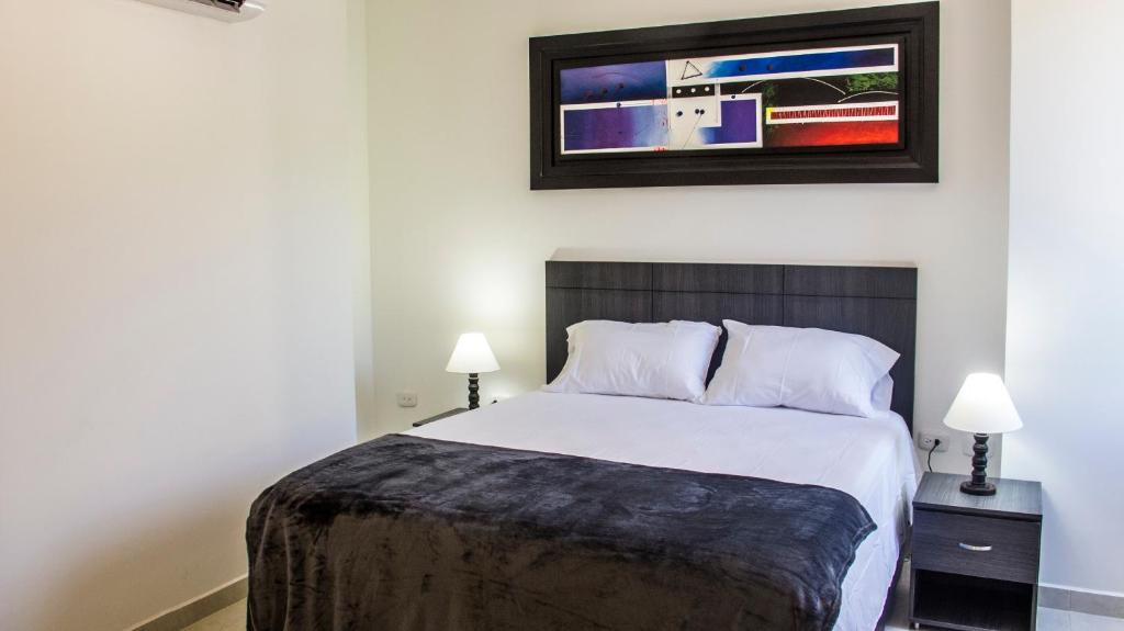 1 dormitorio con 1 cama, 2 lámparas y una foto en la pared en Hotel Viña Del Mar, en Santa Marta