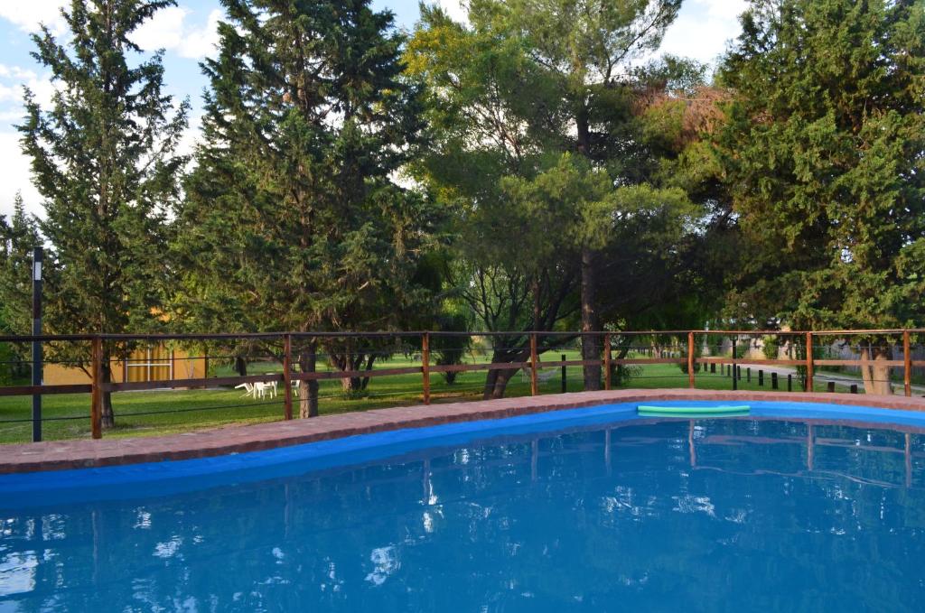 a blue swimming pool in a park with trees at Posada del Viajero San Rafael in San Rafael